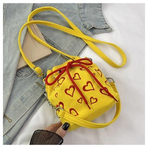 Macro view of yellow corduroy bucket bag with red heart embroidery and woven drawstring
