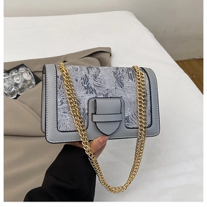 Detail of grey chain crossbody bag featuring floral embroidery and gold metal strap
