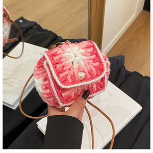 Detail of mini handmade crochet bag with 3D pink floral patterns and a pearl button