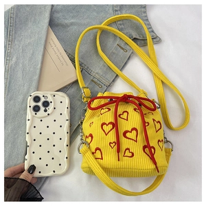 Detail of yellow corduroy bucket bag featuring red heart embroidery and drawstring closure