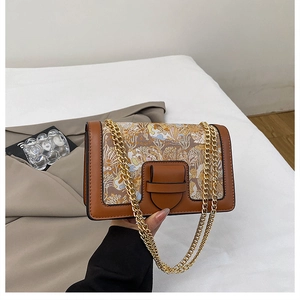 Detail of vintage flap bag with floral embroidery and golden metal chain strap