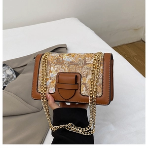Detail of vintage patchwork crossbody bag with floral canvas and gold chain strap