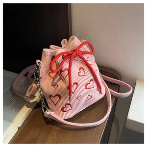 Close-up of pink corduroy bucket bag with red heart embroidery and drawstring bow closure
