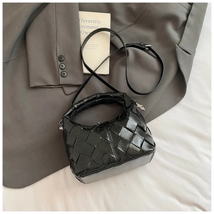Détail du sac à main noir en cuir tressé avec texture brillante et bandoulière