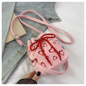 Detail of pink corduroy bucket bag featuring heart embroidery and bow detail on top