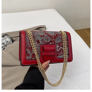 Detail of red crossbody bag with silver embroidery and golden chain strap for women