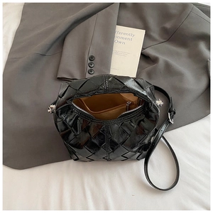 Détails de la doublure, poche zippée et texture tressée du sac à bandoulière noir brillant