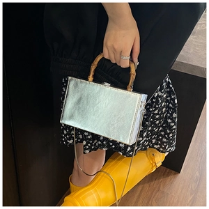 Close-up of a silver rectangular box clutch featuring a vintage bamboo top handle and chain