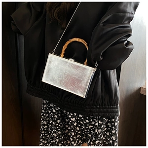 Close-up of silver textured box bag with natural bamboo handle and metal chain