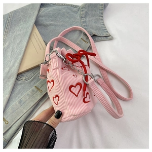 Close-up of pink corduroy bucket bag with red heart embroidery and silver chain