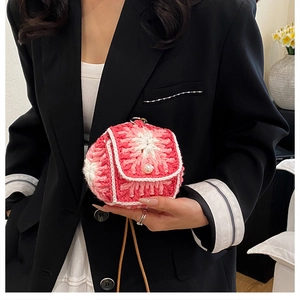 Close-up of a handmade crochet mini bag with pink floral patterns and a pearl button