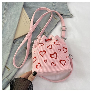 Detailed shot of pink corduroy bucket bag featuring red heart embroidery and strap