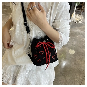 Detail of black corduroy bucket bag with red heart embroidery and chain strap
