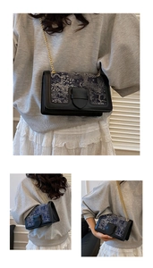 Detail of vintage crossbody bag with blue embroidery pattern and gold chain strap