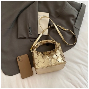 Détail du sac bandoulière tressé doré avec sangle réglable et finition brillante