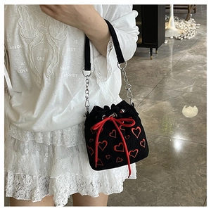 Detail of black knit bucket bag with red heart embroidery and drawstring bow