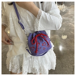 Close-up of purple corduroy bucket bag with red heart embroidery and drawstring chain