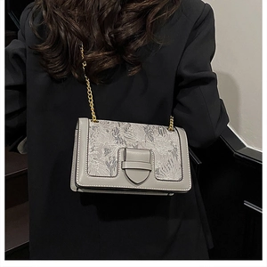 Detailed view of floral pattern fabric shoulder bag with gold chain and metal buckle