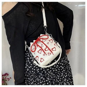 Close-up of a white mini bucket bag with red heart patterns and drawstring closure