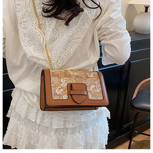 Detail of vintage floral embroidered crossbody bag with gold chain strap on white lace dress