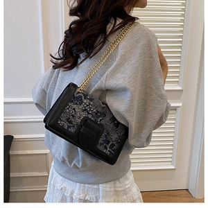 Detail of embroidered shoulder bag with gold chain strap and vintage pattern