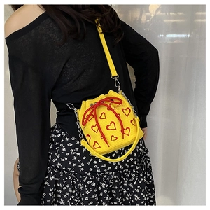 Detailed view of yellow bucket bag with red heart embroidery and drawstring closure