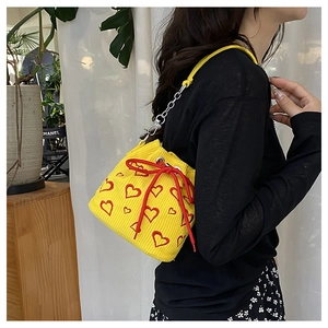 Yellow corduroy bucket bag with red heart embroidery and chain strap detail view
