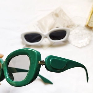 Détail de lunettes de soleil ovales vertes avec branches larges et charnière robuste
