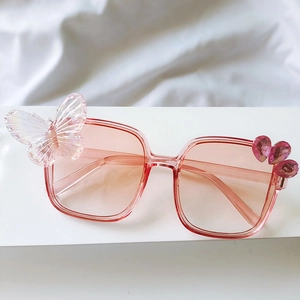 Détail de lunettes de soleil roses pour enfants avec papillon et joyaux en cœur