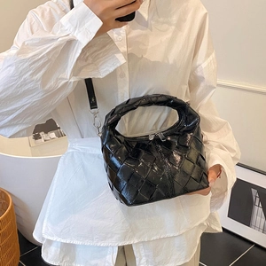 Sac bandoulière tressé noir brillant avec détails argentés porté par un mannequin