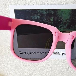 Close-up of pink children's sunglasses showing polarized lens effect with a test card