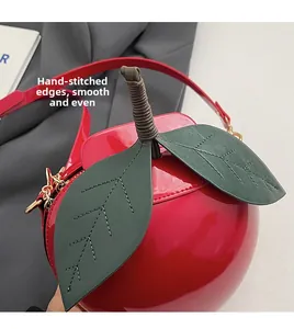 Detailed view of apple-shaped bag featuring glossy red patent leather and green leaf