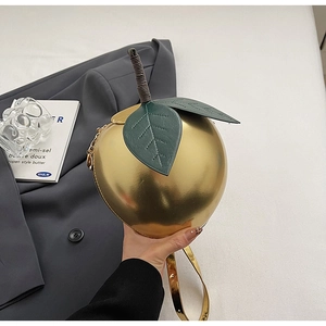 Close-up of a metallic golden apple-shaped handbag with green leaf detail and gold strap