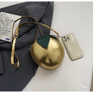 Macro shot of creative apple-shaped golden shoulder bag with leaf and stem details