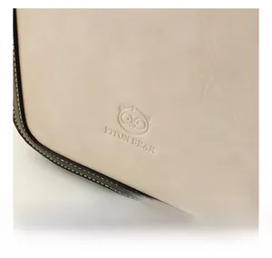 Detail of off-white faux leather bag showing Piton Bear embossed logo and fine texture