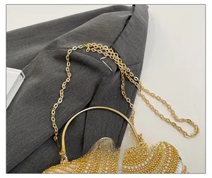 Close-up of golden sequins and white pearls on evening bag with round handle