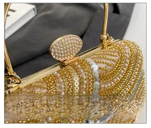 Close-up of golden evening clutch featuring intricate pearl embroidery and crystal clasp