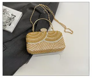 Detail of sequined evening bag with pearls, metal handle and chain next to smartphone