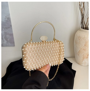 Detail of evening clutch featuring white faux pearls and a golden metal handle