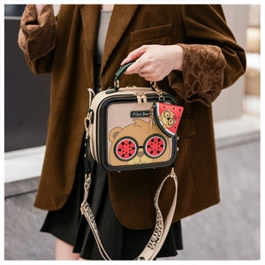 Close-up of Piton Bear cartoon bag with watermelon charm and wide textile shoulder strap