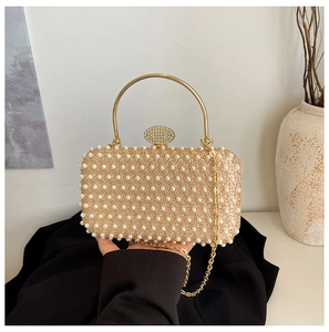 Detailed macro view of champagne gold evening bag with white pearls and rhinestone clasp