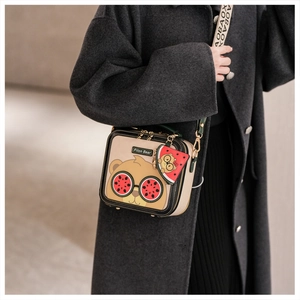Detail of cute bear crossbody bag with watermelon charm and lettered wide strap