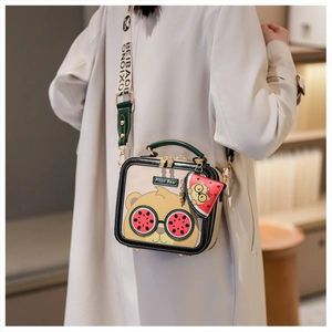Detail of square cartoon bear shoulder bag with wide strap and mini watermelon pouch