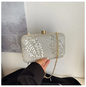 Detailed close-up of silver sequin feather patterns with crystal buckle on evening bag
