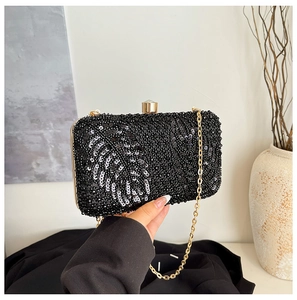 Detail of sequins leaf pattern on black evening clutch with gold spherical clasp