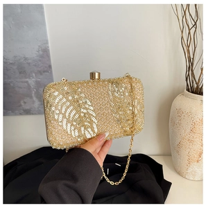 Macro shot of champagne gold evening bag with sequin leaf patterns and metal clasp