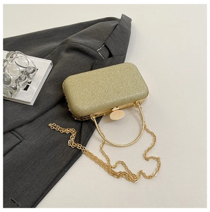Close-up of golden sequin evening bag with elegant metal handle and fine chain strap