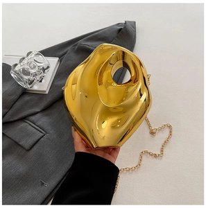 Detail of a golden geometric acrylic evening bag with a metallic mirror finish and chain strap