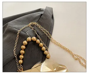 Close-up of champagne gold evening bag with geometric diamond facets and beaded handle
