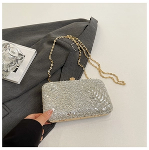 Detail of silver sequin evening clutch with rhinestone leaf patterns and gold chain